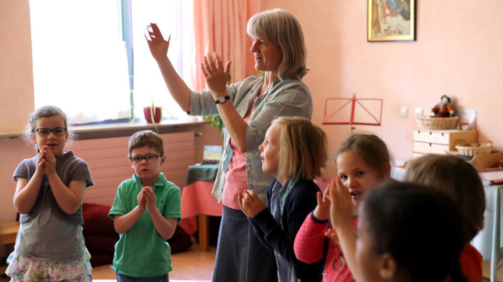 Kinder musizieren gemeinsam mit Lehrerin im Klassenraum.