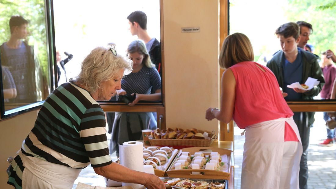 Ehrenamtliche bereiten in der Cafeteria belegte Brötchen für die Pause vor.