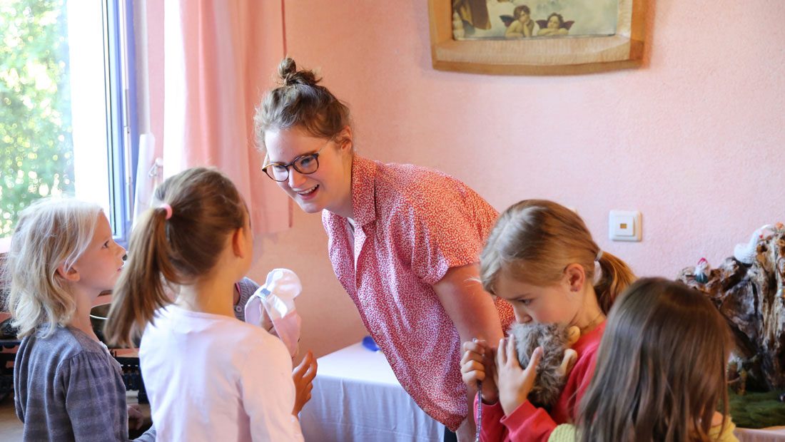 Lächelnde Lehrkraft begleitet ein Kind im Klassenraum.