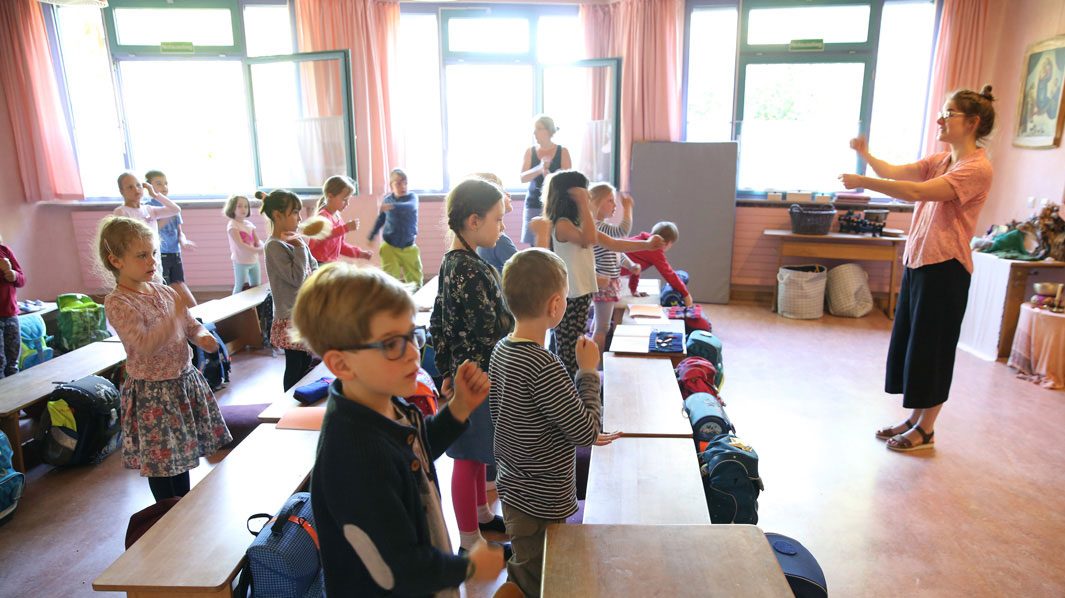 Lehrkraft und Kinder bewegen sich gemeinsam im Klassenraum.